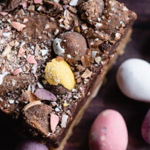Mini Egg Brookie from our Easter Brownie Box. The the right are various pastel coloured chocolate Mini Eggs. To the left and centre of the image is a Brookie with crushed Mini Eggs on top.