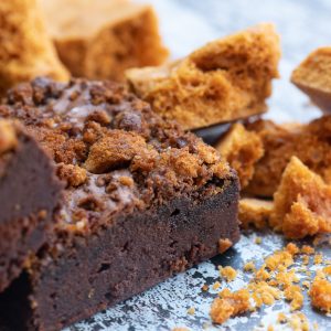 An image of Brownie and The Beans honeycomb brownies. This is a close up image and the brownies are laid on a marbled background. There are chunks of honeycomb next the the brownies. The image is to promote a 12 month Brownie Box Subscription.