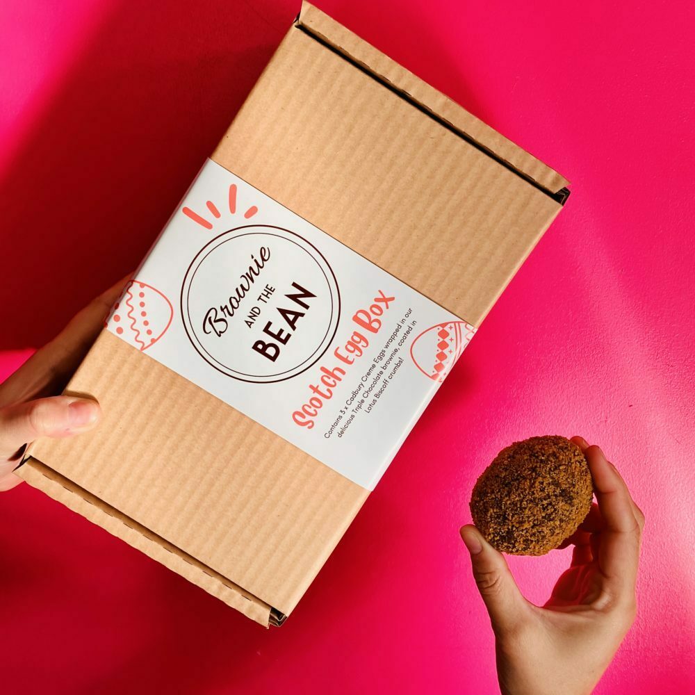 Scotch Egg Brownie and box against a pink background
