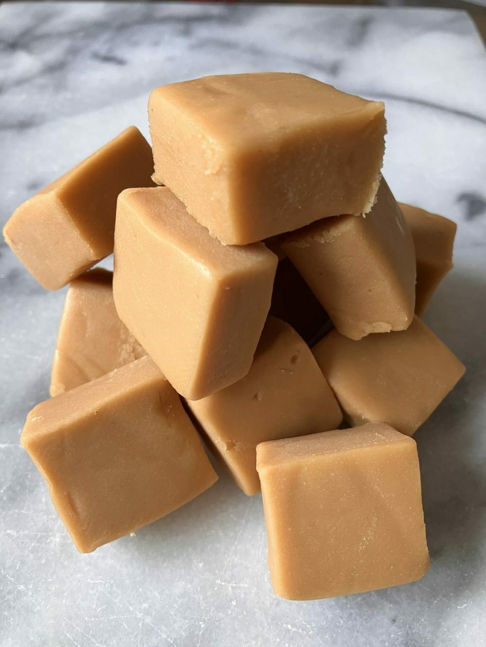Piles of fudge in a cube on a marbled background.