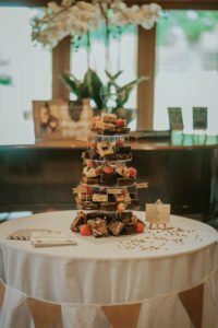 A wedding brownie cake is stacked in a tier on a round table with a white table cloth.
