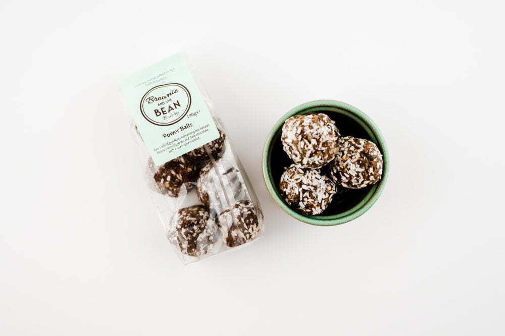 Our vegan treats are featured in a pottery stoneware bowl and also in a packet, lying down on a white background.