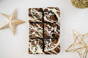 6 Christmas Triple Chocolate brownies are on a warm white background with 3 x festive baubles scattered around the edges.