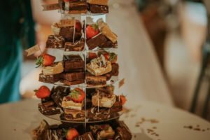 A close up of a brownie wedding stack with strawberries dotted around.