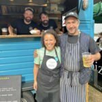 Charlotte smiling with some street food trailers at Aldeburgh Food and Drink Festival