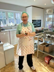 Sue our brownie and cake sous chef is smiling in the bakery, holding some handcrafted Christmas Cake.