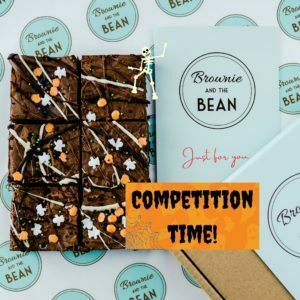6 Halloween themed brownies on branded Brownie and the Bean greaseproof paper. The words Competition Time are written in spooky black and orange writing. There is also a greeting card and a brownie box.