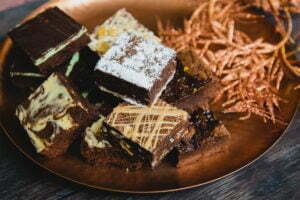 A selection of brownies are on a copper plate, with some copper coloured glittery garlands on.