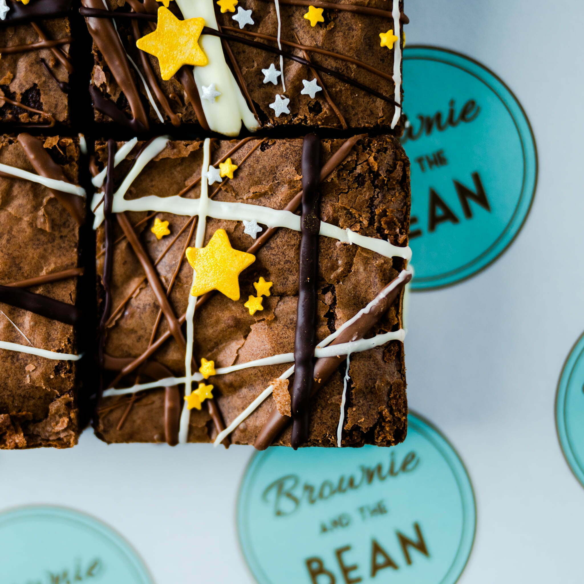 Father's Day brownies on a branded greaseproof. The brownies have spashes of white and dark chocolate on them and gold and silver stars in different sizes.