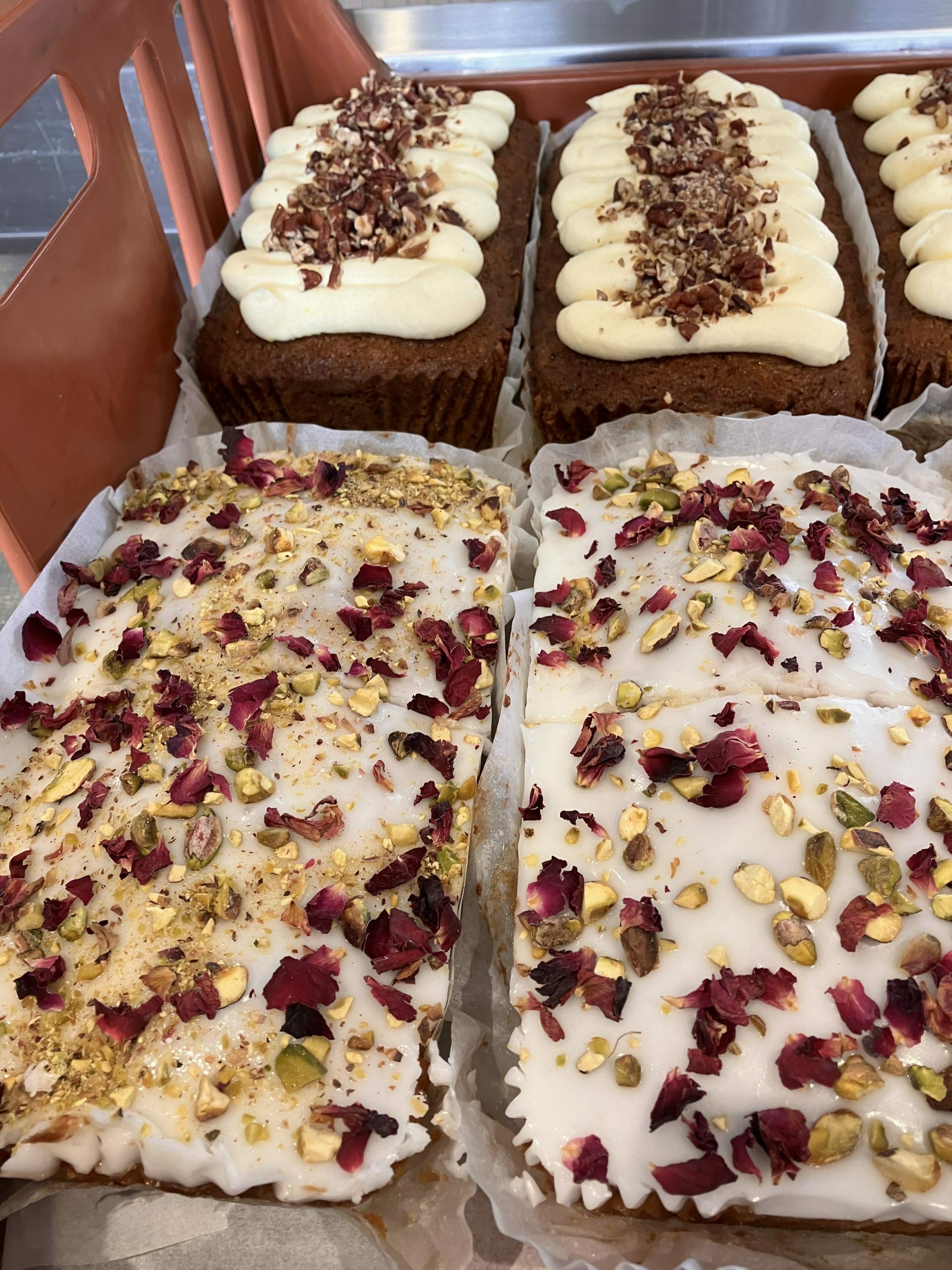 the best wholesale cakes are lined up in a tray. The front two are Persian Love Cakes and heavily decorated. The back 3 are carrot cake loaves.
