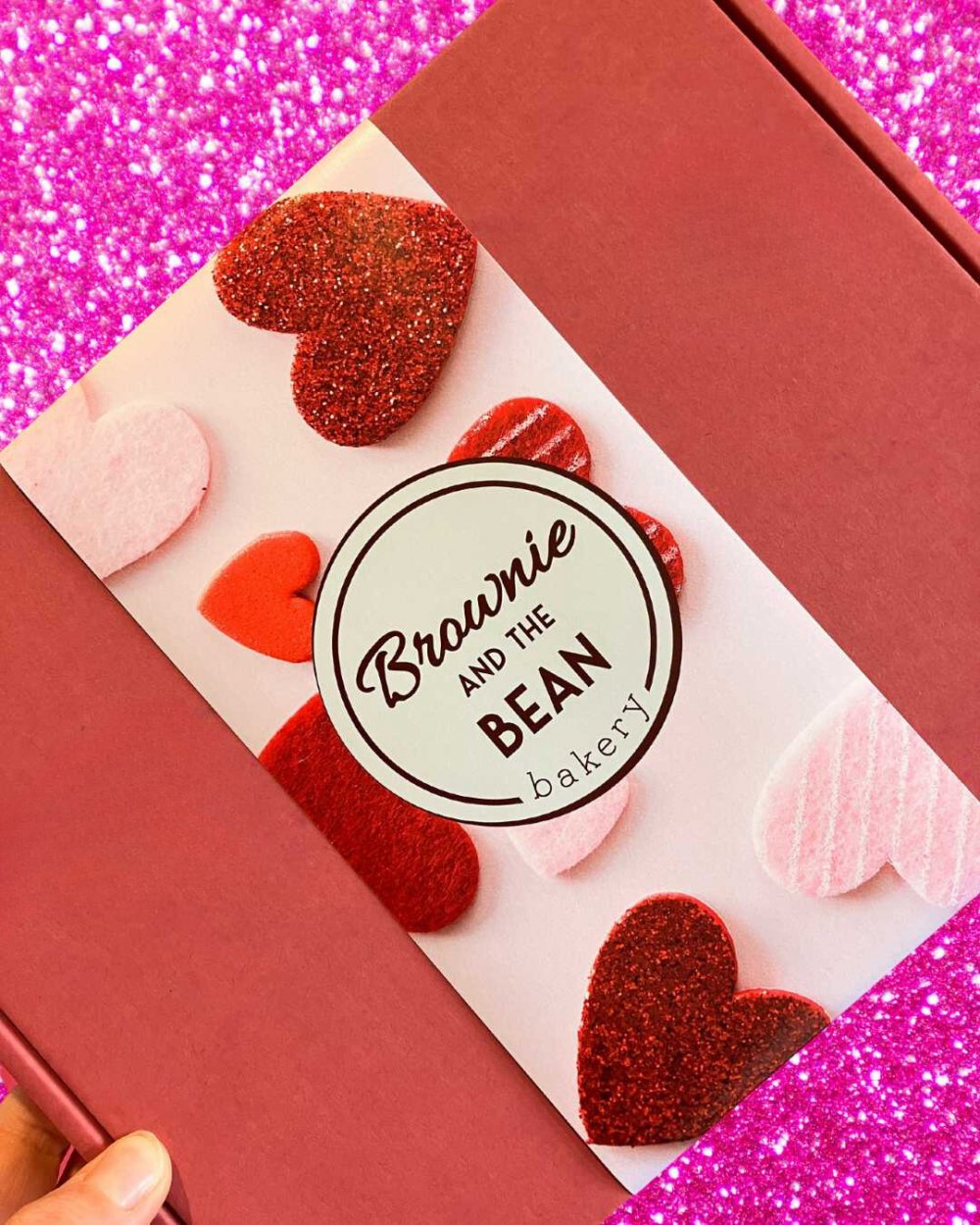 Valentine's Day Brownie Box with pink glittered background and hearts.